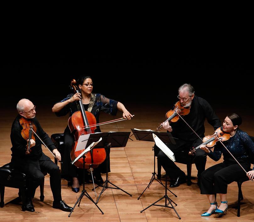 4 performers seated on stage playing instruments